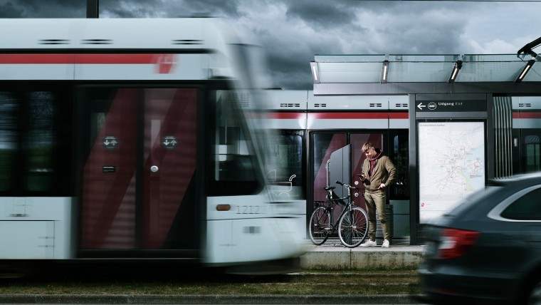 Ung mand på station, hvor letbanen kører forbi