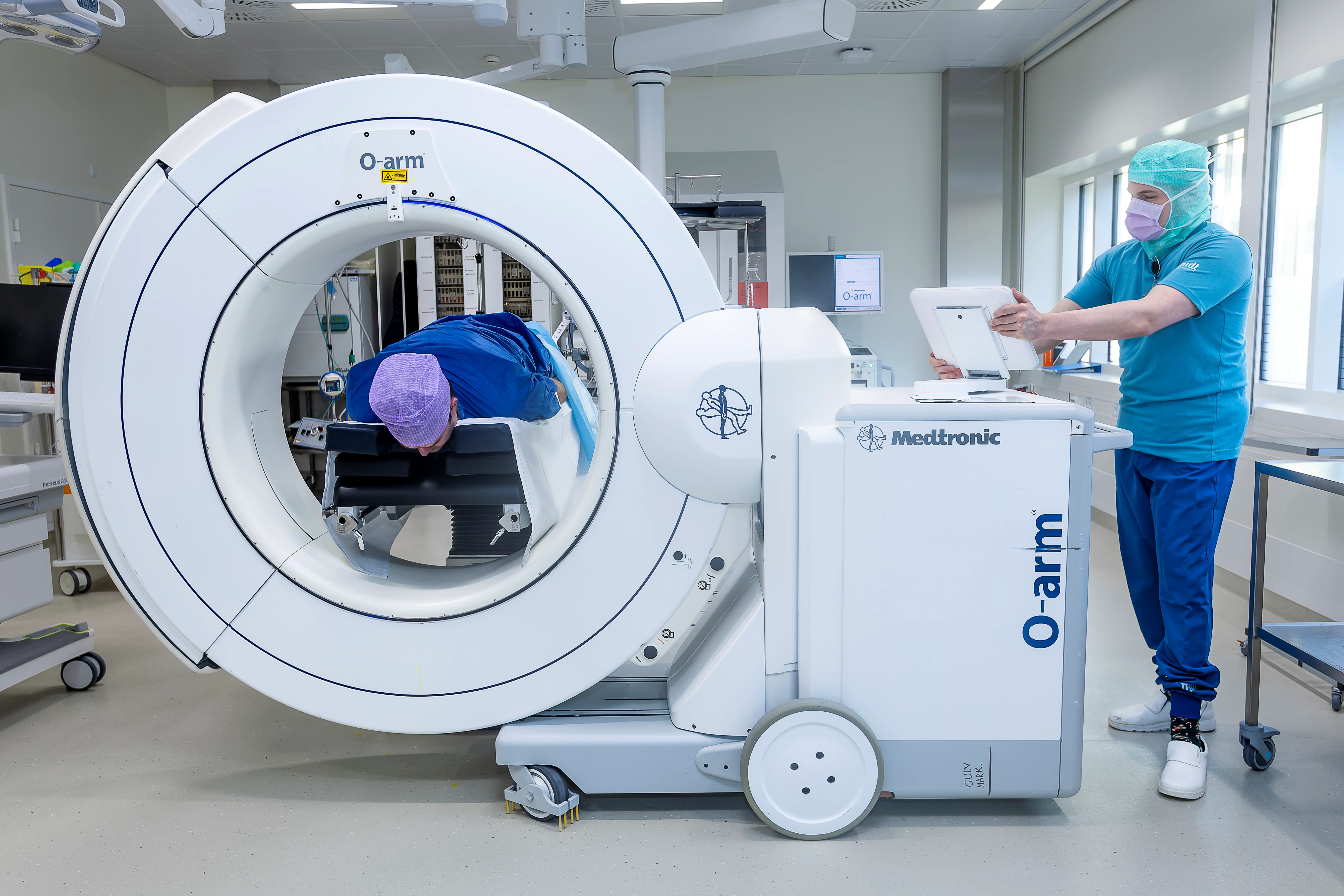 Patient ligger i scanner, mens en læge står ved siden af.